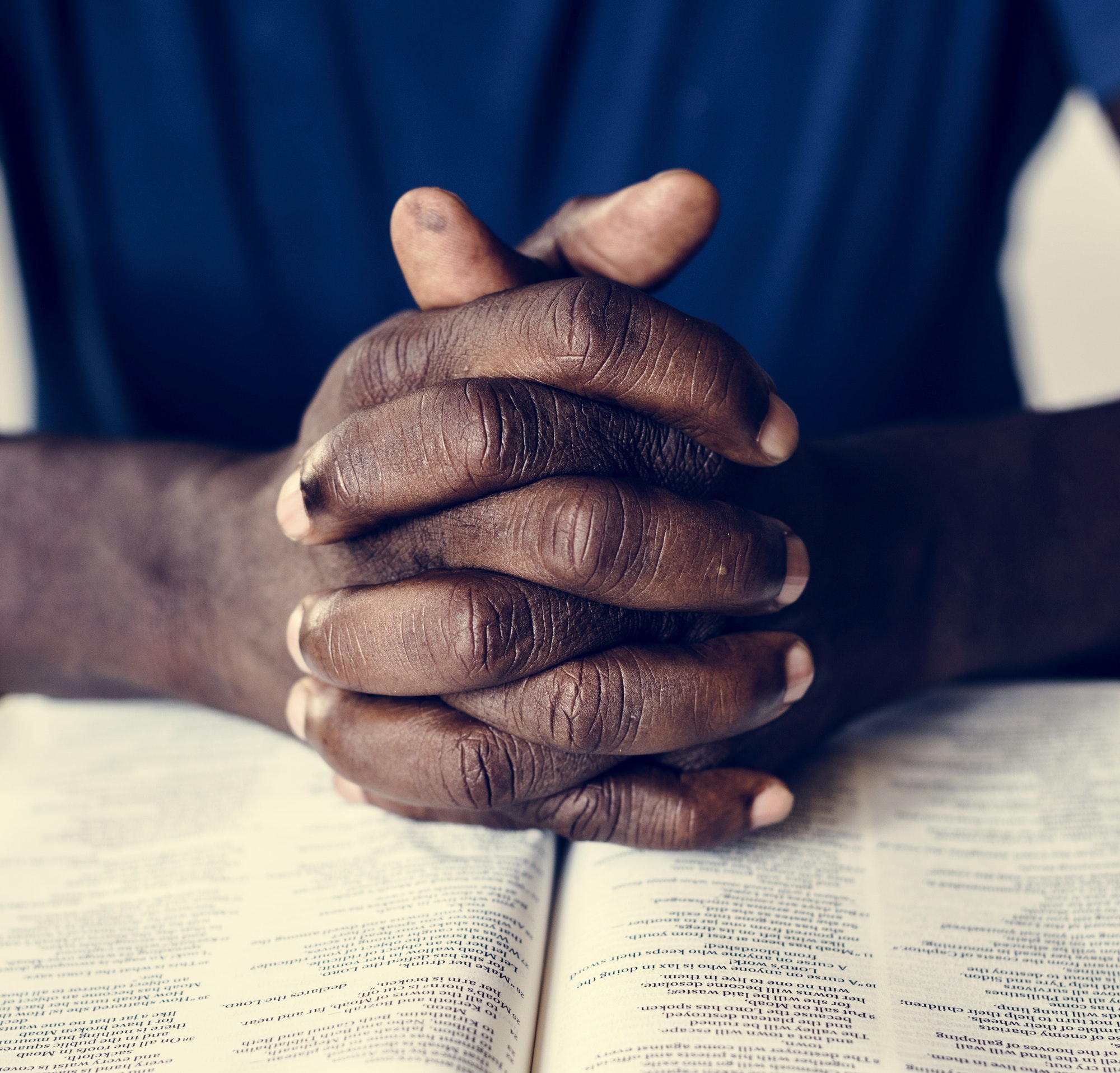 African American male hands resting on an open bible